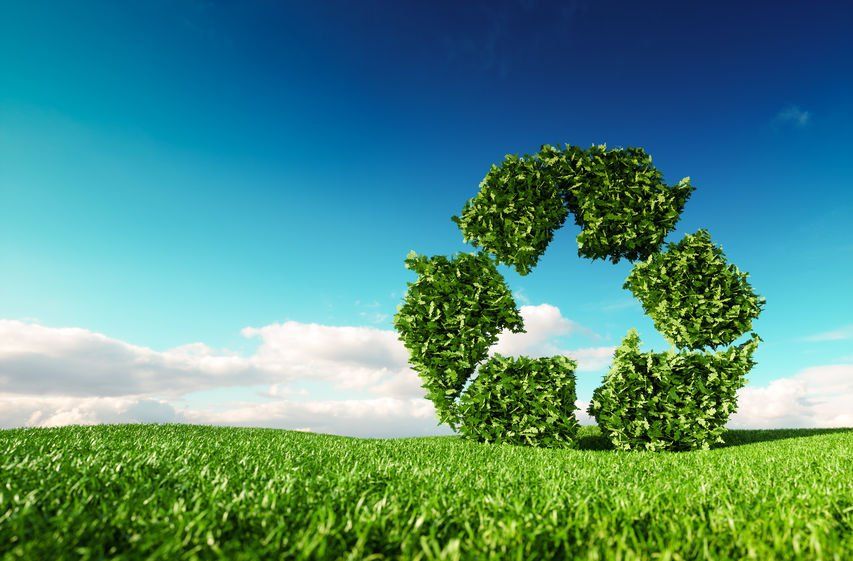 Recycling symbol over green grass representing 100 percent recycled paper tubes