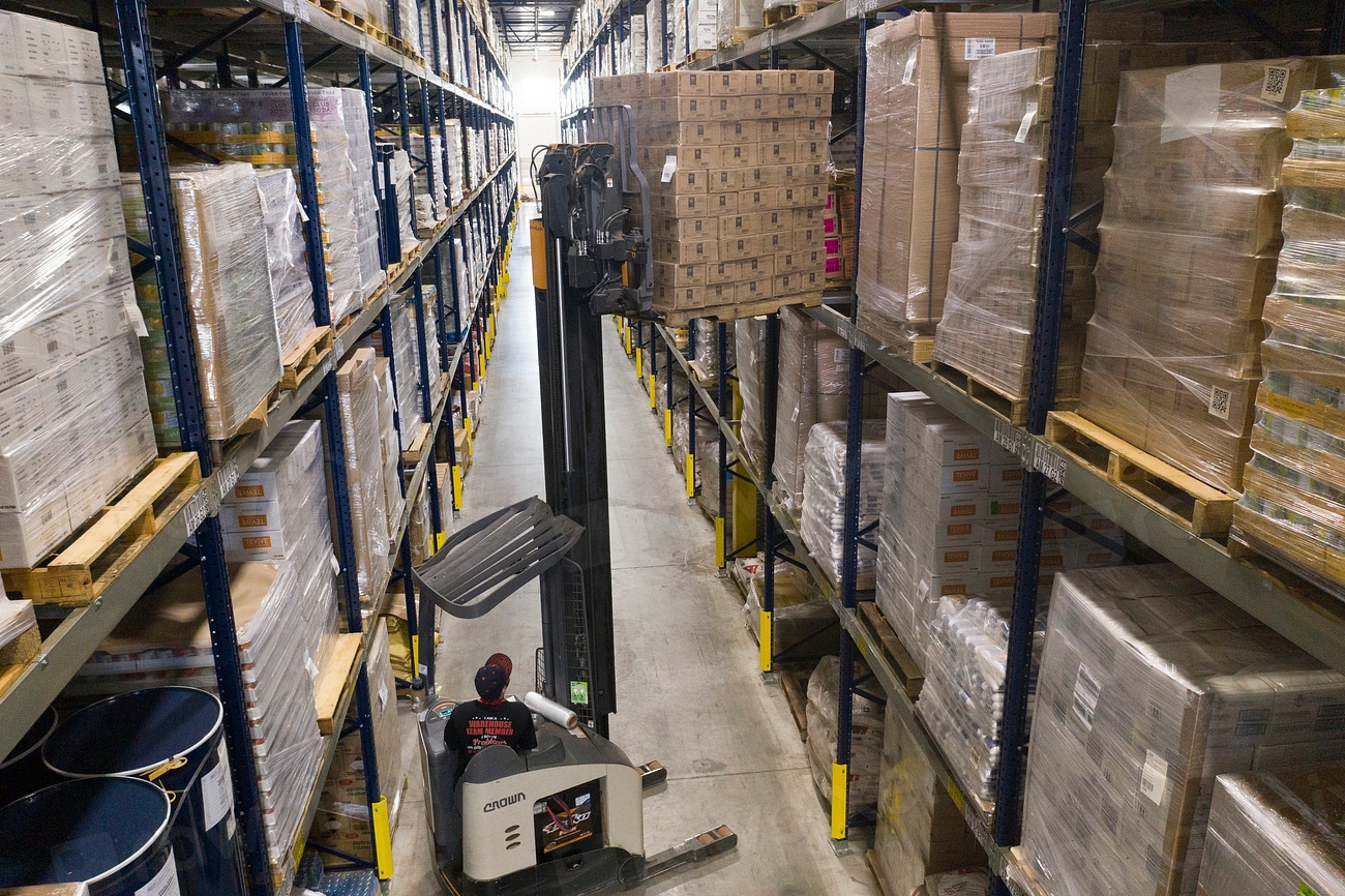 Warehouse racking aisle stocked with shipping cartons and tubes